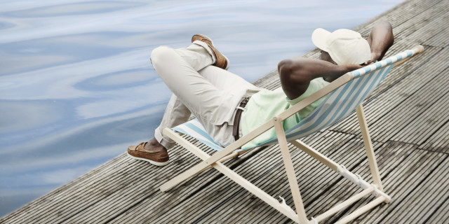 Man relaxing by lake on deck chair